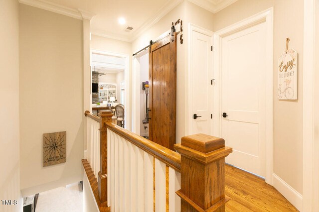 hall featuring ornamental molding, light hardwood / wood-style flooring, and a barn door