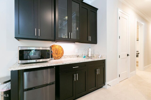 bar with light carpet, light stone counters, sink, crown molding, and stainless steel appliances