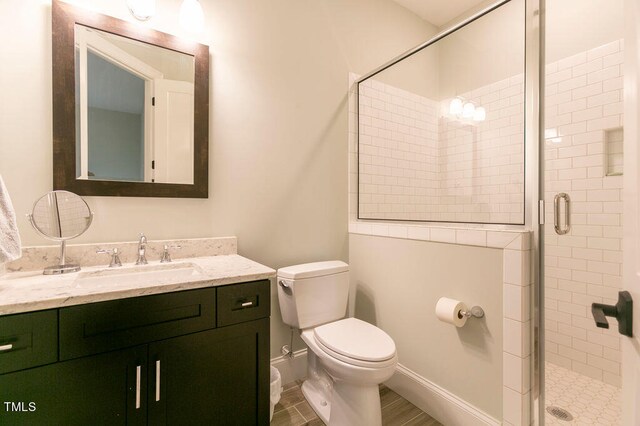 bathroom with vanity, toilet, and a shower with shower door