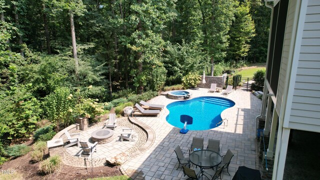 view of pool featuring a patio, a fire pit, and an in ground hot tub