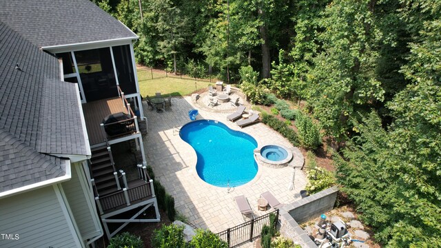 view of swimming pool featuring a grill, a patio area, an outdoor fire pit, and a sunroom