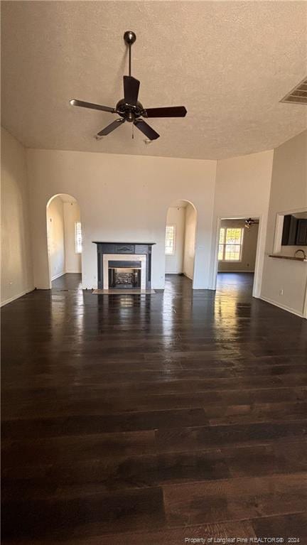 unfurnished living room with dark wood-type flooring, a textured ceiling, and ceiling fan