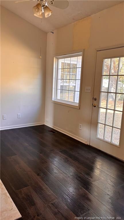 spare room with a healthy amount of sunlight, dark wood-type flooring, and ceiling fan