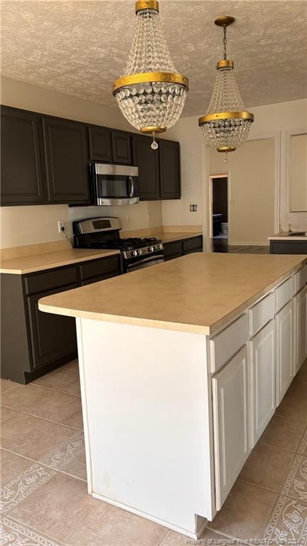 kitchen featuring appliances with stainless steel finishes, a kitchen island, a textured ceiling, pendant lighting, and white cabinets