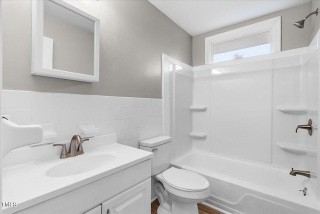 full bathroom featuring vanity, bathtub / shower combination, toilet, and tile walls