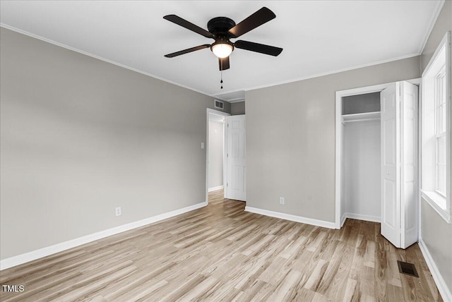 unfurnished bedroom with a closet, crown molding, light wood-type flooring, and ceiling fan