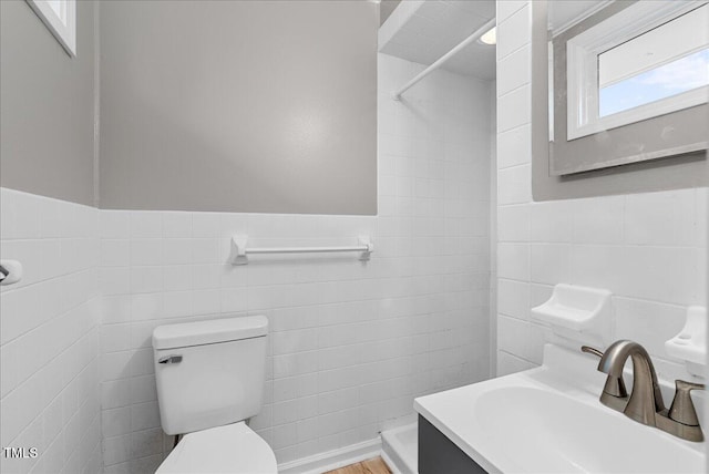 bathroom featuring vanity, tile walls, a tile shower, and toilet