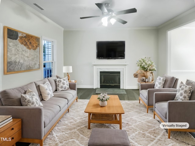 living room with crown molding, a premium fireplace, light wood-type flooring, and ceiling fan