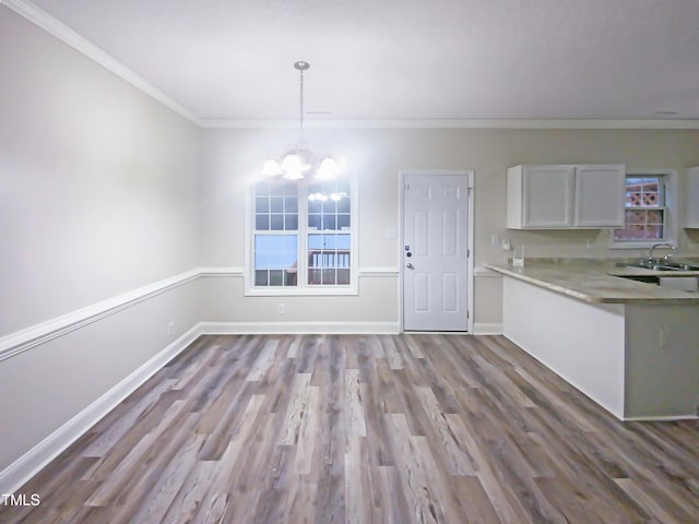 kitchen with hanging light fixtures, an inviting chandelier, white cabinetry, ornamental molding, and light hardwood / wood-style floors