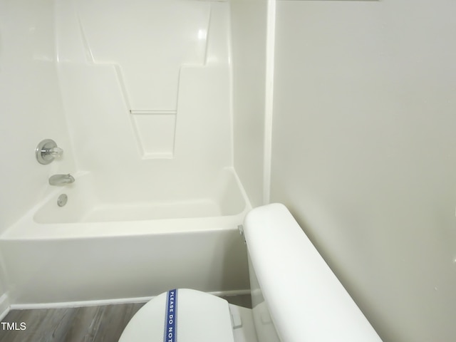 bathroom featuring toilet, hardwood / wood-style flooring, and bathing tub / shower combination