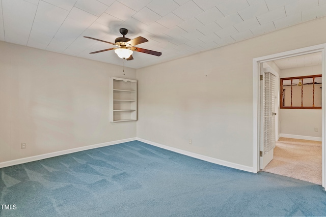 empty room featuring built in shelves, ceiling fan, and carpet floors