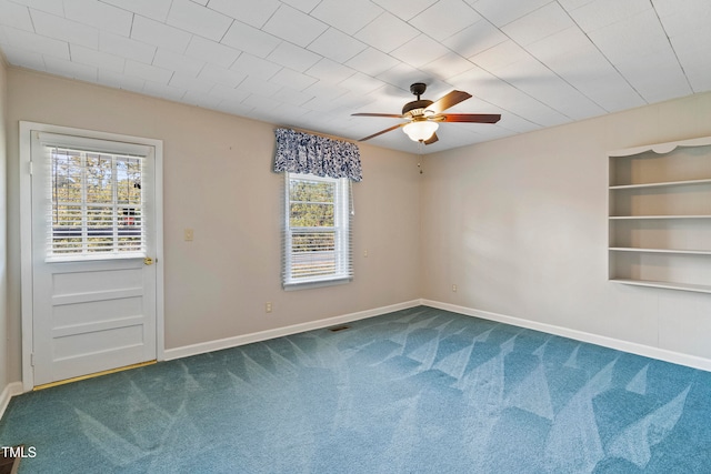 empty room featuring ceiling fan, built in features, and carpet