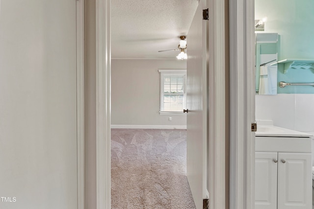 hallway with a textured ceiling and light carpet