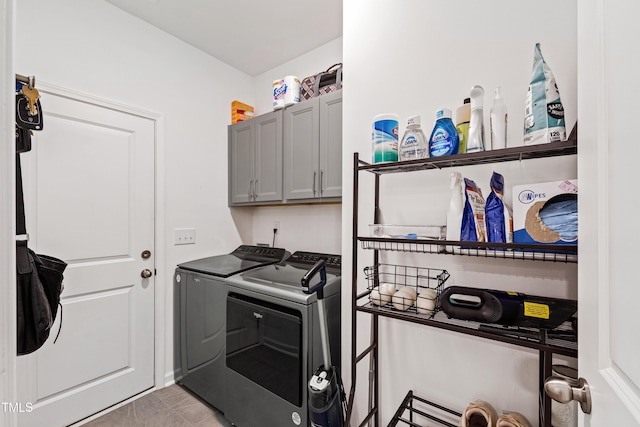 clothes washing area with separate washer and dryer and cabinet space