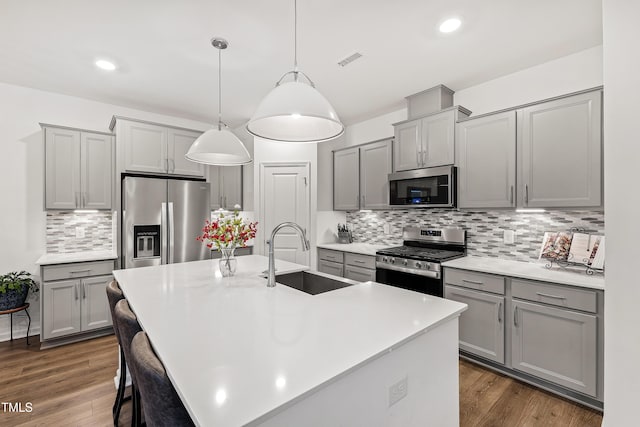kitchen featuring stainless steel appliances, a sink, gray cabinets, and recessed lighting