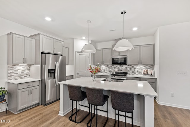 kitchen featuring appliances with stainless steel finishes, gray cabinetry, tasteful backsplash, and recessed lighting
