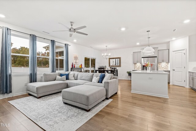 living area with ceiling fan, recessed lighting, light wood-style floors, and a chandelier