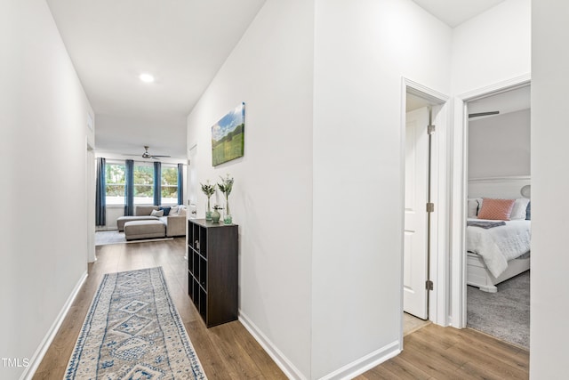 hall featuring wood finished floors, baseboards, and recessed lighting
