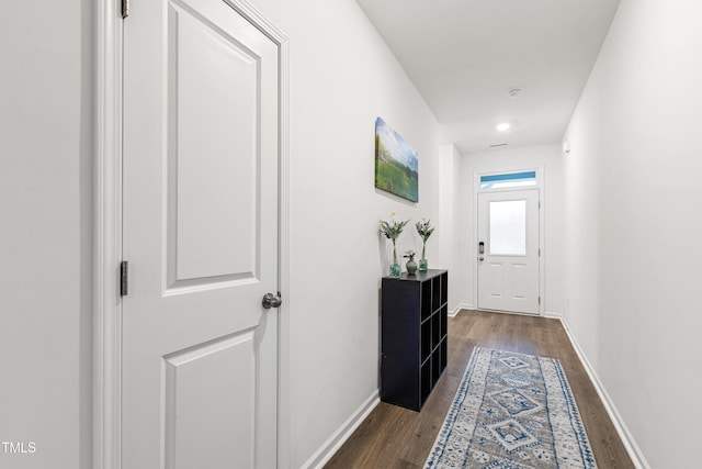 hallway featuring dark wood finished floors and baseboards