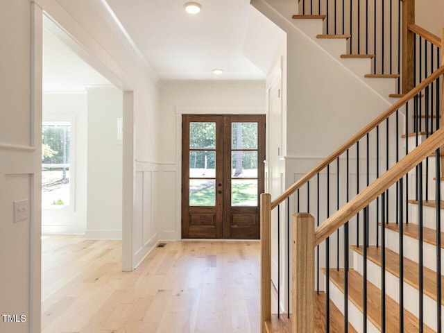 entryway featuring french doors, ornamental molding, and light hardwood / wood-style flooring