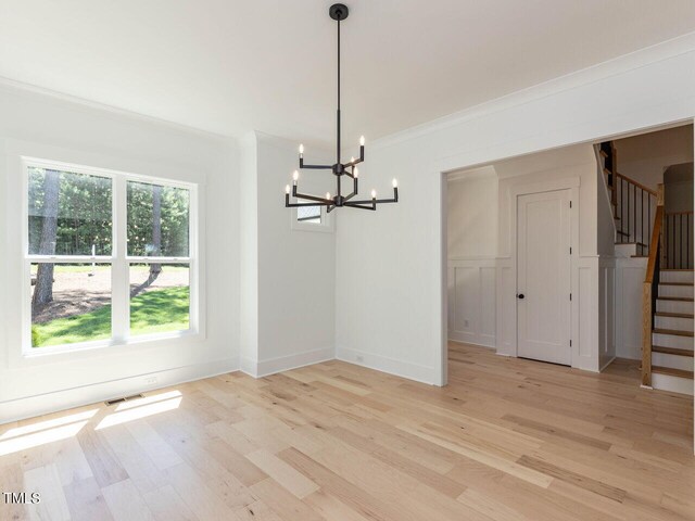 103 Brandy Ml, Pittsboro, NC 27312 - unfurnished dining area featuring light wood-type flooring, a chandelier, stairs, crown molding, and baseboards
