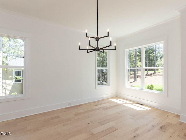 unfurnished dining area with light hardwood / wood-style floors, an inviting chandelier, and ornamental molding