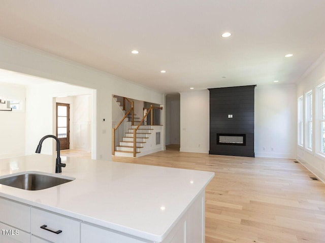 103 Brandy Ml, Pittsboro, NC 27312 - kitchen with a sink, white cabinets, light countertops, a large fireplace, and light wood finished floors