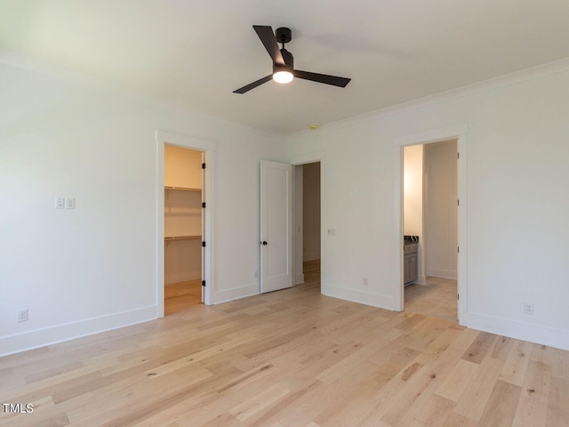 unfurnished bedroom with ensuite bath, ceiling fan, a closet, light wood-type flooring, and a spacious closet