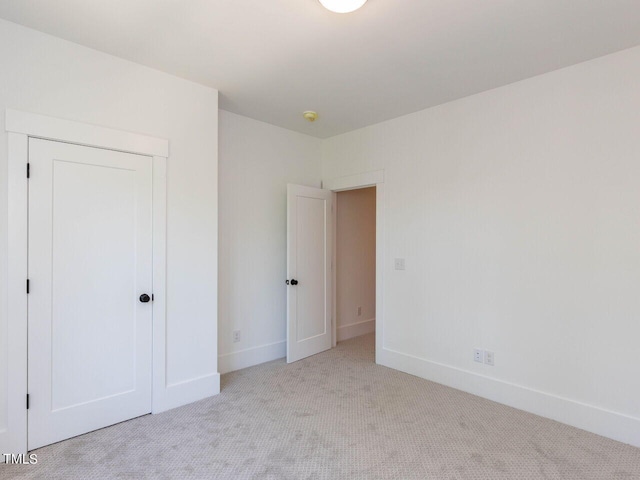 unfurnished bedroom featuring light colored carpet and a closet