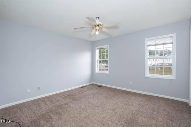 carpeted spare room featuring ceiling fan and a healthy amount of sunlight