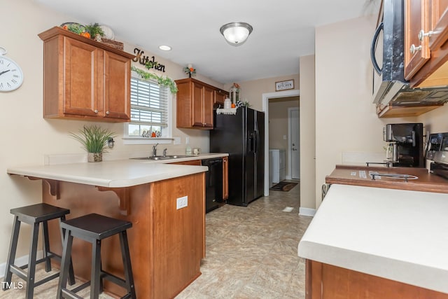 kitchen featuring black appliances, kitchen peninsula, sink, and a breakfast bar area