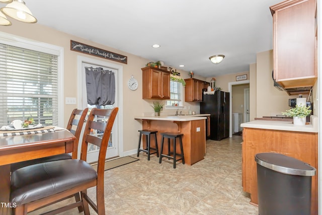 kitchen with a kitchen bar, kitchen peninsula, black fridge, and sink