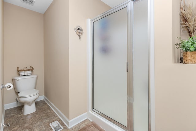 bathroom featuring a shower with shower door and toilet