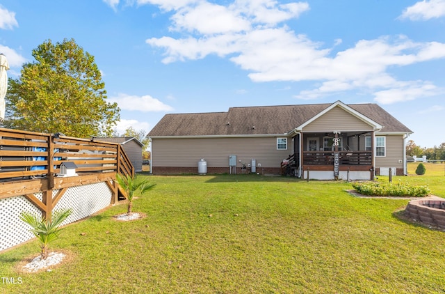 back of property featuring a wooden deck, a sunroom, and a yard