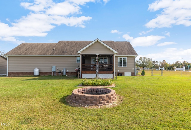 back of property with a lawn, a fire pit, and ceiling fan