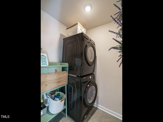 washroom featuring stacked washer and clothes dryer and tile patterned flooring