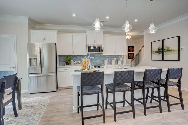 kitchen featuring stainless steel appliances, decorative light fixtures, light wood-type flooring, and white cabinets