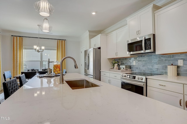 kitchen featuring hanging light fixtures, appliances with stainless steel finishes, white cabinetry, sink, and light stone counters