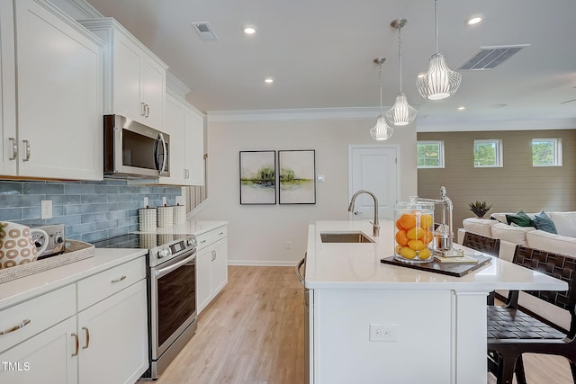 kitchen with a center island with sink, sink, crown molding, decorative light fixtures, and stainless steel appliances