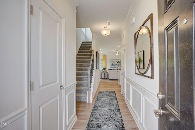 hall with light hardwood / wood-style floors and ornamental molding