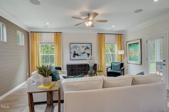 living room featuring crown molding, light hardwood / wood-style flooring, a healthy amount of sunlight, and ceiling fan