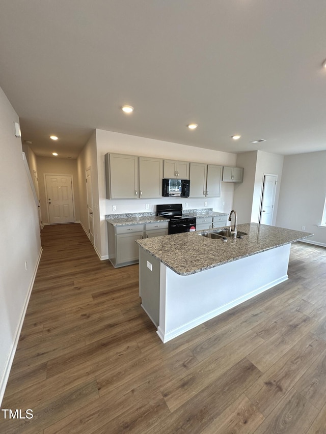 kitchen featuring black appliances, dark wood-type flooring, gray cabinets, and a sink