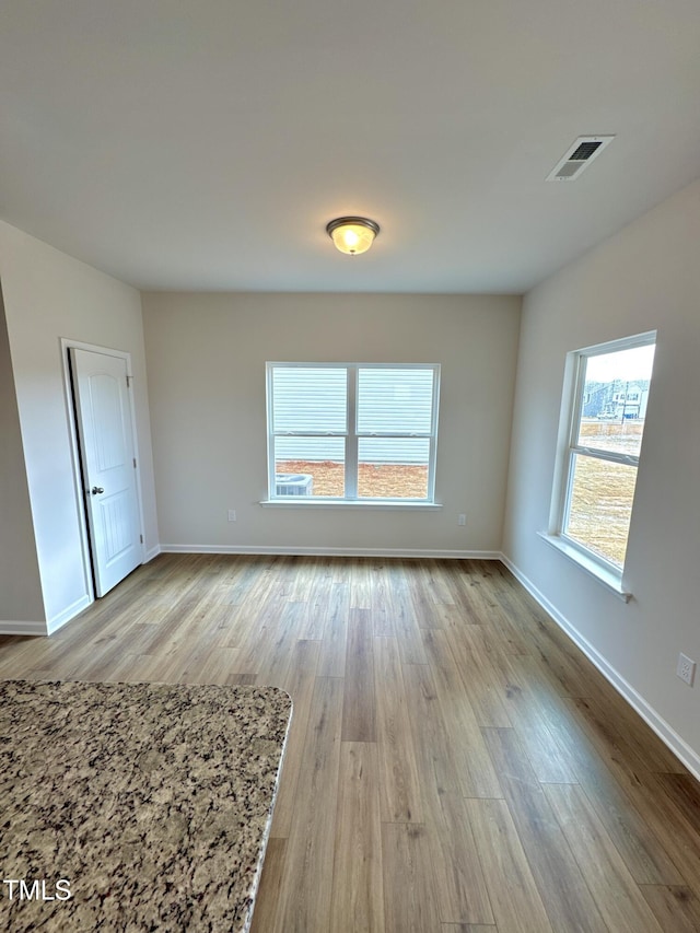 spare room with visible vents, baseboards, and wood finished floors