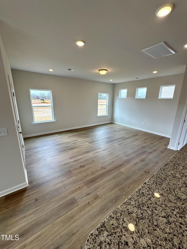 spare room with baseboards, wood finished floors, and recessed lighting