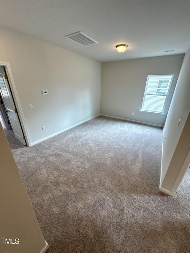 spare room featuring carpet floors, baseboards, and visible vents