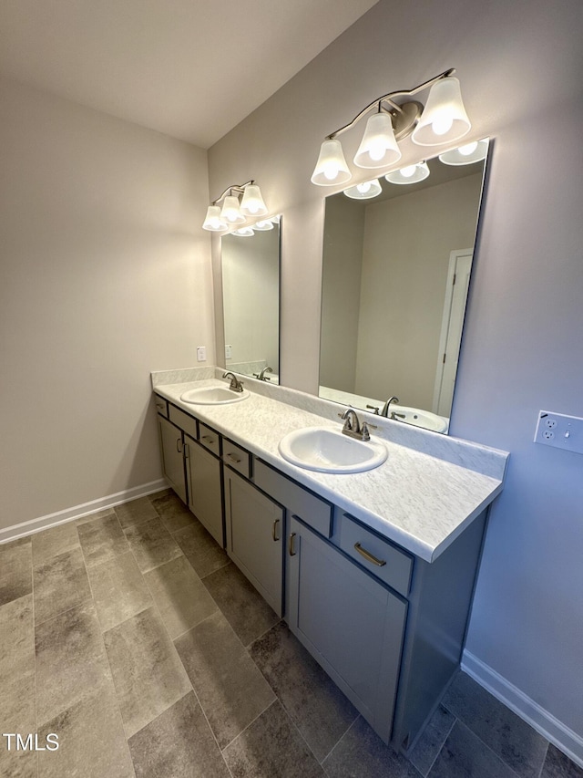 bathroom with a sink, baseboards, and double vanity