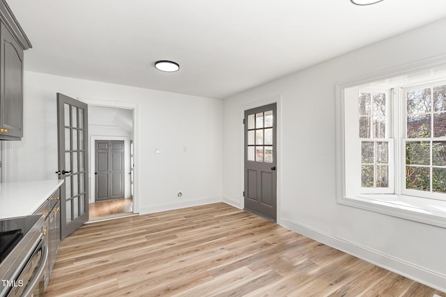 unfurnished dining area with french doors and light wood-type flooring