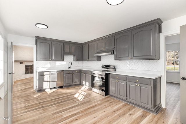 kitchen with sink, gray cabinets, tasteful backsplash, light hardwood / wood-style floors, and stainless steel appliances