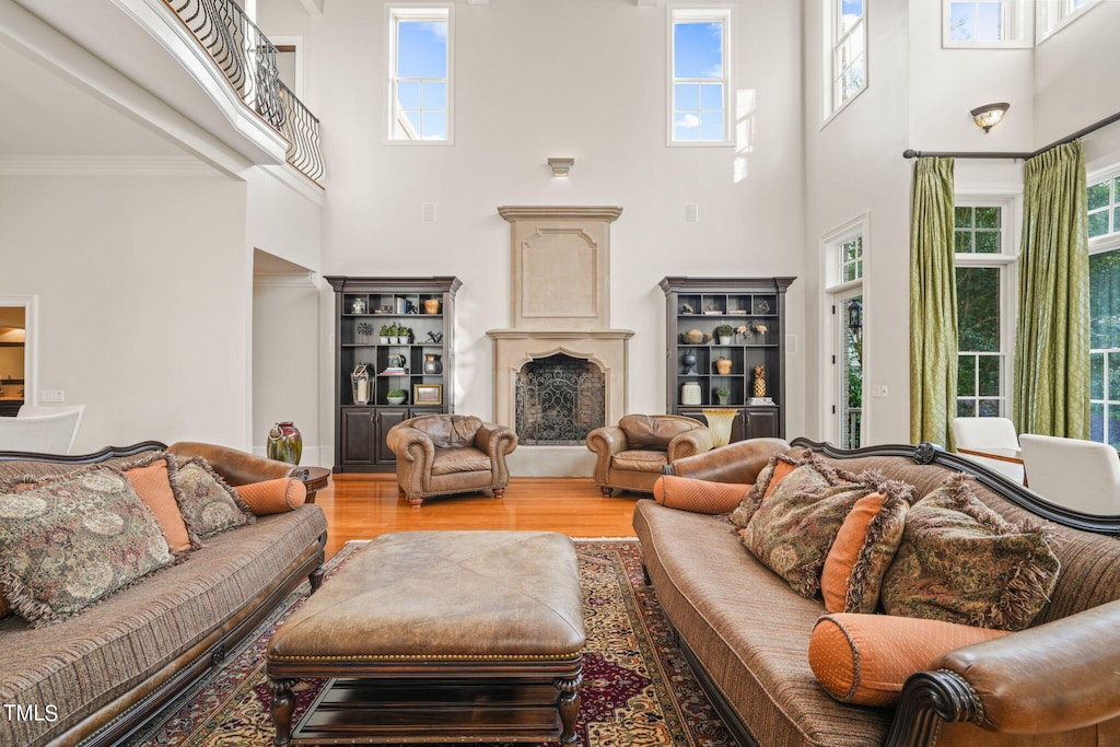 living room with light hardwood / wood-style floors, crown molding, and a towering ceiling