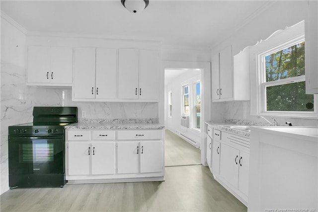 kitchen featuring light hardwood / wood-style flooring, black stove, white cabinets, and a healthy amount of sunlight